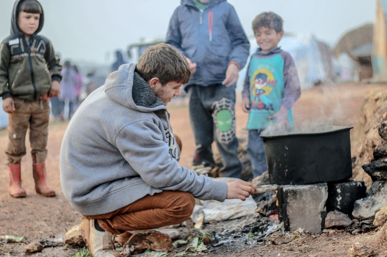 services-02 A group of children cooking over an outdoor stove at a refugee camp in Idlib, Syria.