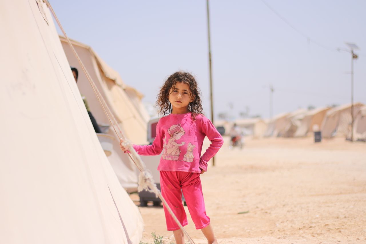 services-01 A young girl stands by a tent in a refugee camp in Idlib, Syria.