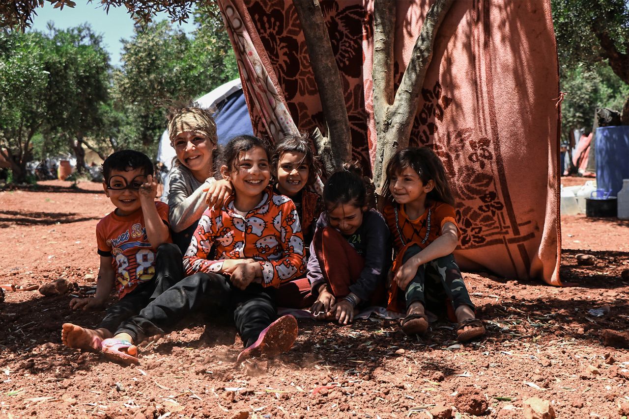 services-03 Group of happy children playing and smiling outdoors in a refugee camp in Idlib, Syria.