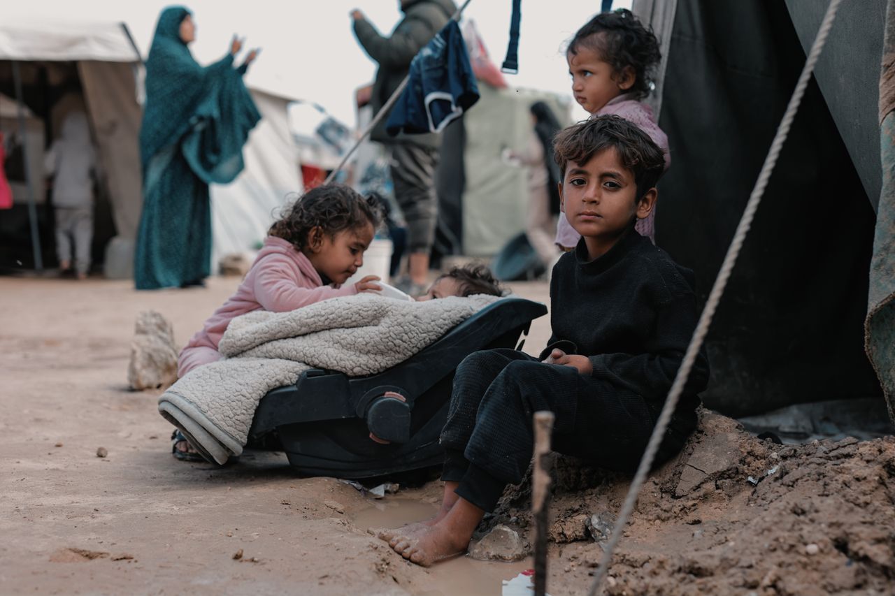 Children sitting in a refugee camp, highlighting human resilience amidst challenging conditions.